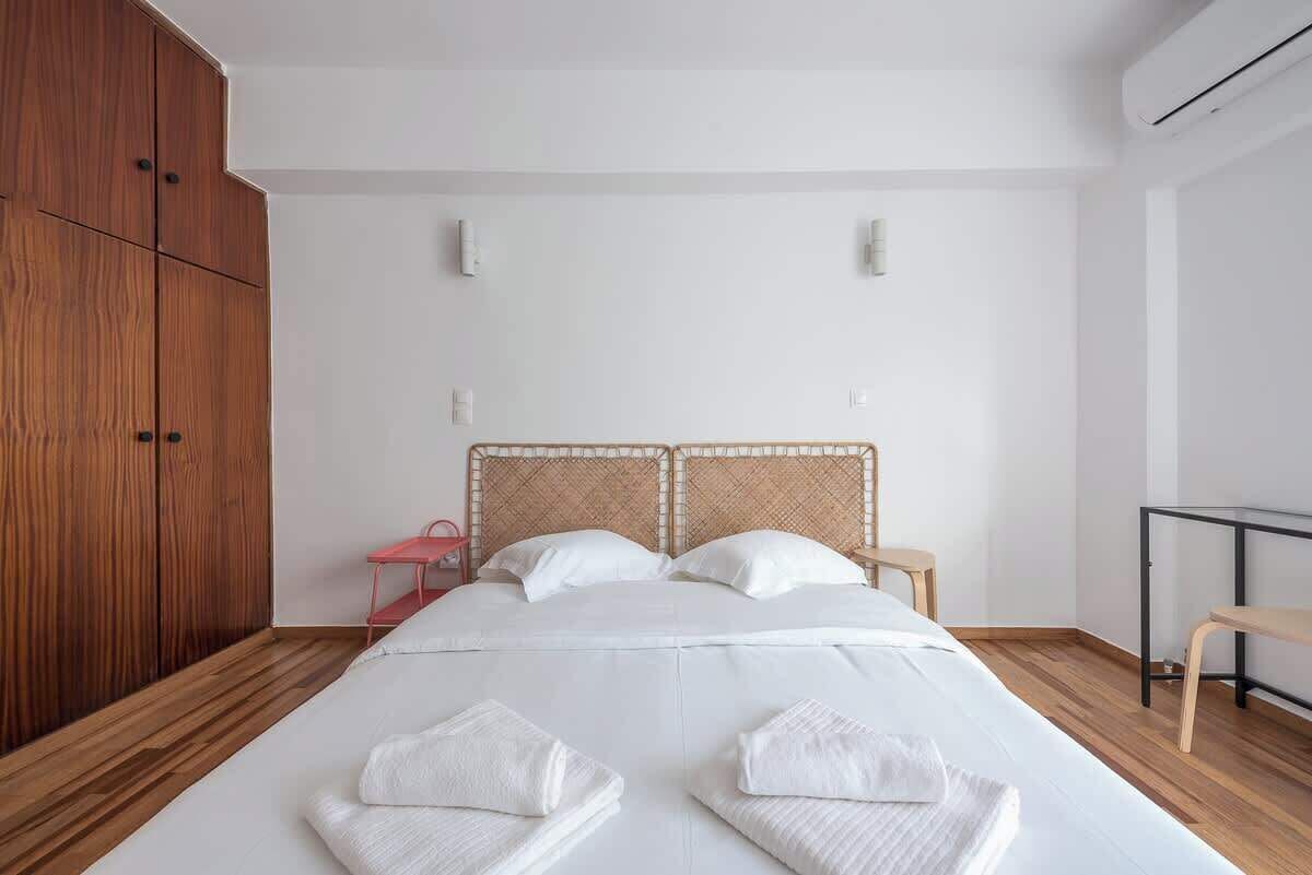 A hotel room with a large bed, wooden wardrobe, and a small desk.