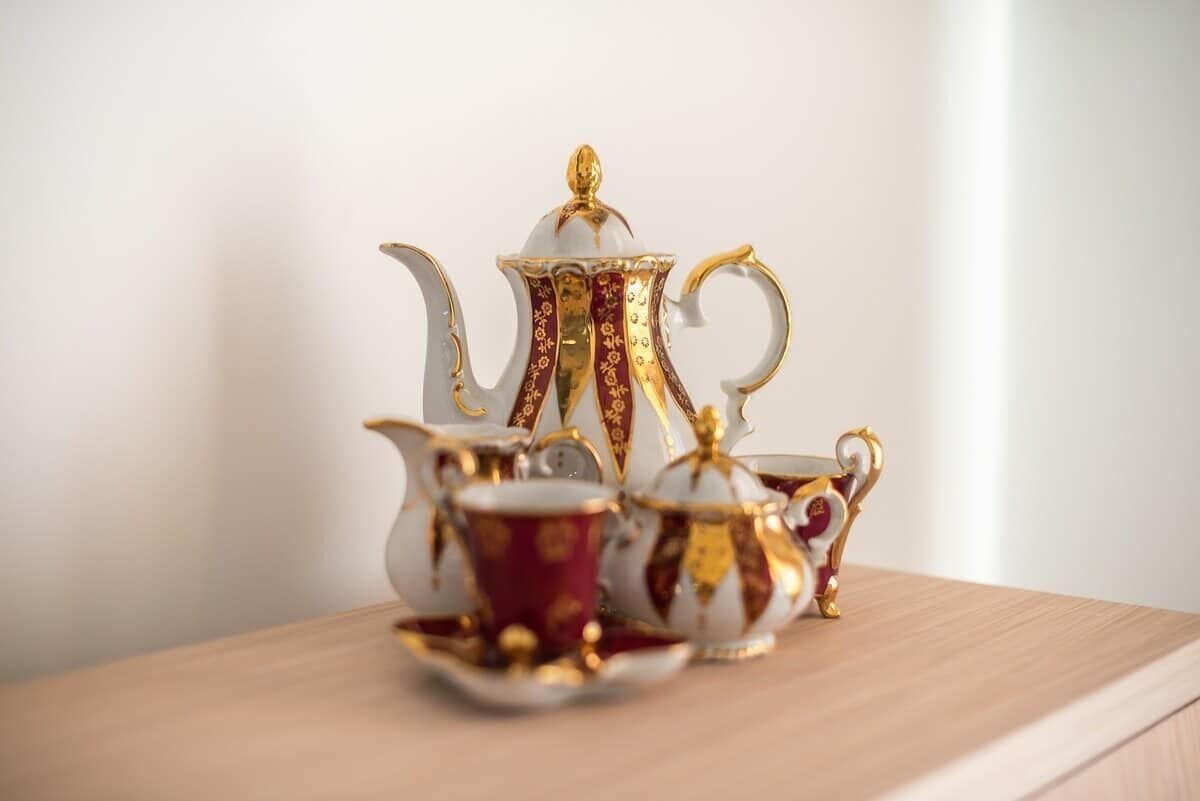 A tea set with a teapot, creamer, and cups on a wooden surface.