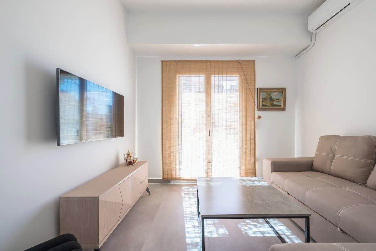 Un salon moderne comprenant un canapé, une table basse, un téléviseur fixé au mur et une porte coulissante donnant sur une vue agréable.