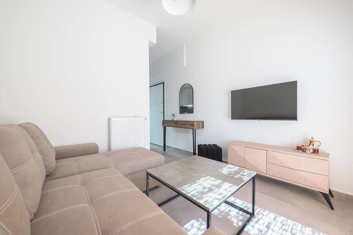 A modern living room with a sofa, a coffee table, a TV mounted on the wall, and a wooden cabinet.
