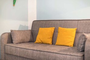 A grey sofa with two mustard-colored cushions. - Zen Hive, in Peaceful Kypseli (Athens)