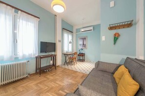 A living room with a sofa, a television, a table, and a chair. - Zen Hive, in Peaceful Kypseli (Athens)