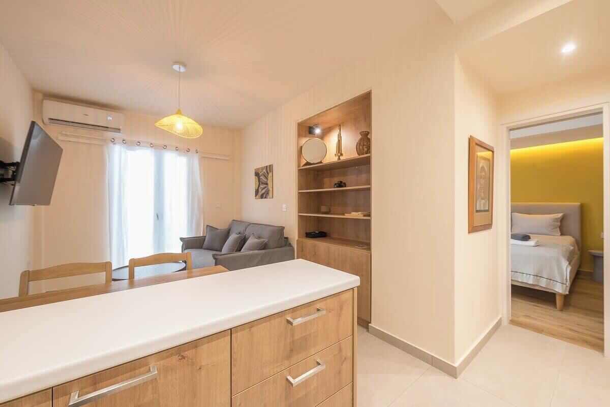 A modern kitchen with wooden cabinets, a white countertop, and a hanging pendant light.
