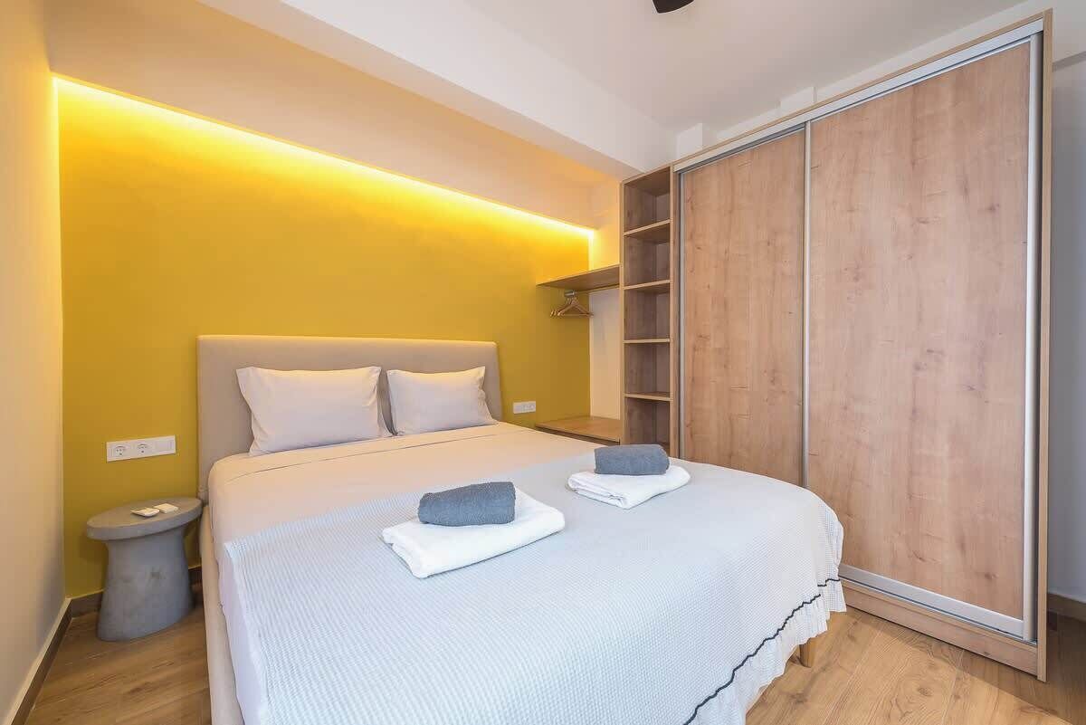 Ein Schlafzimmer mit einem Bett, Nachttischen, einem Kleiderschrank und einem an der Wand befestigten Regal.