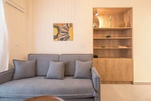 A living room with a grey sofa, a wooden cabinet with shelves, and a wall-mounted artwork. - Zen Euphoria, Exarchia (Athens)