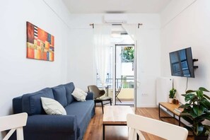 Ein modernes Wohnzimmer mit einer Couch, einem Couchtisch und einem an der Wand befestigten Fernseher.