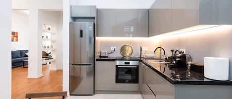 A compact kitchen with a refrigerator, oven, and modern appliances.