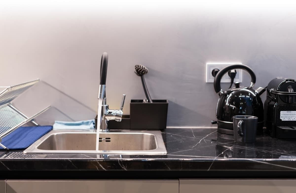 A kitchen with a sink, kettle, and coffee maker.