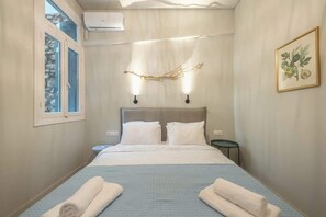 Ein Hotelzimmer mit Bett, Nachttisch, Wandleuchte und Fenster.