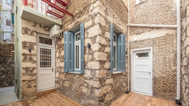 A narrow stone building with wooden flooring and blue shutters. - Zen Yard, Exarchia (neapoli) (Athens)