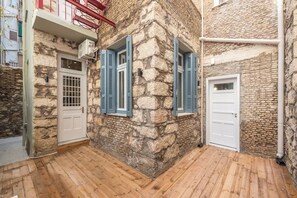 A narrow stone building with wooden flooring and blue shutters. - Zen Yard, Exarchia (neapoli) (Athens)