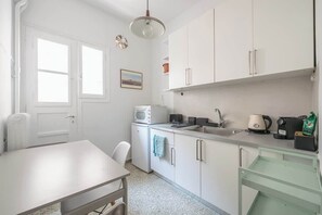 A compact kitchen with white cabinets, a microwave, a sink, and a coffee maker. - Modern Exarcheia Apt w/Balcony, Walk to Cafes & (Athens City)