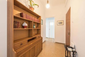 A hallway with a wooden bookshelf, a potted plant, and a door. - Modern Exarcheia Apt w/Balcony, Walk to Cafes & (Athens City)