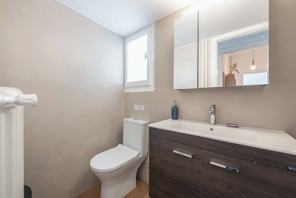 A bathroom with a toilet, a sink, a mirror, and a cabinet.