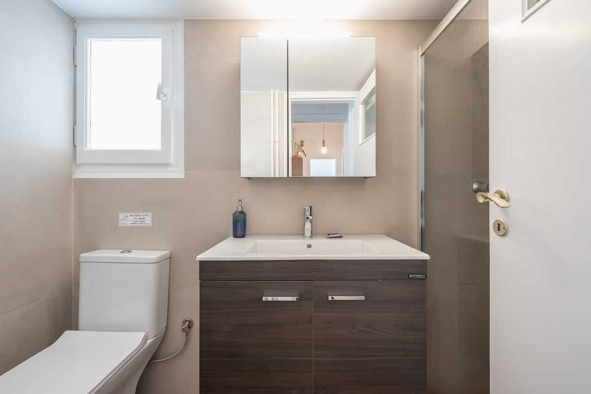 Une salle de bain comprenant des toilettes, un lavabo, un miroir et un meuble de rangement.