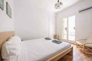 A bedroom with a bed, a chair, a window, and a door. - Modern Exarcheia Apt w/Balcony, Walk to Cafes & (Athens City)