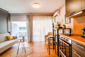 Eine moderne Küche mit Essbereich, einer Couch und Blick ins Freie.