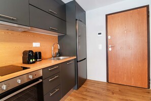 Eine moderne Küche mit Einbauofen, Edelstahlkühlschrank, Holzschränken und einer Holzarbeitsplatte.