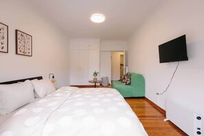 A bedroom with a bed, a green chair, a television, and a wardrobe. - Zen Sofokleous, Psirri (Athens City)