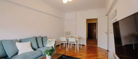 A living room with a sofa, a coffee table, and a dining area with chairs and a table.