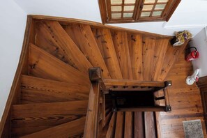 A wooden spiral staircase with a handrail, a fire extinguisher, and a vase with flowers on the landing. - zoodochou pigis 101 · Zen Penthouse, Exarchia (Athens City)