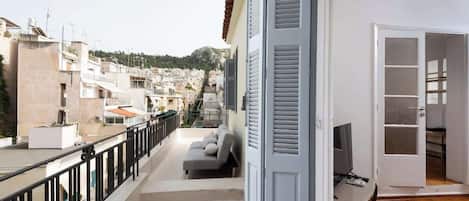 Un balcon avec un canapé, une télévision et un plancher en bois.