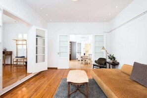 A spacious living area with a wooden floor, a sofa, a table, and a chair. - zoodochou pigis 101 · Zen Penthouse, Exarchia (Athens City)