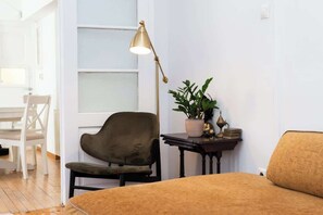 Ein Zimmer mit einem Bett, einem Schreibtisch mit Lampe, einem Stuhl und einer Zimmerpflanze.