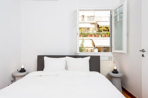 A bedroom with a bed, two bedside tables, a window with a view of a balcony, and a radiator. - zoodochou pigis 101 · Zen Penthouse, Exarchia (Athens City)
