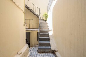 A narrow stairway leading to a landing with a metal railing, flanked by walls with a tiled floor. - Zen Amazing, Exarchia (Athens)