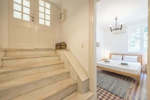 A staircase leading to a bedroom with a bed, a chandelier, and a checkered floor. - Zen Amazing, Exarchia (Athens)