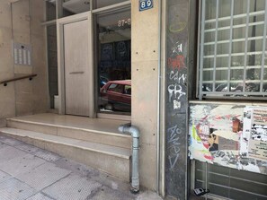 A building entrance with a door marked '89', steps leading up to it, and a window with a poster. - Zen Intimate, Exarchia (Athens City)