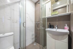 A modern bathroom with a glass shower enclosure, a white sink, and a mirror above the sink. - Zen Intimate, Exarchia (Athens City)