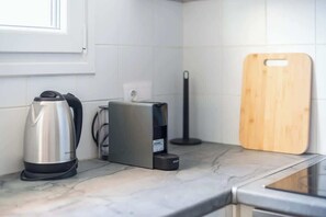 A kitchen with a kettle, a coffee maker, a toaster, and a wooden cutting board on the counter. - Zen Intimate, Exarchia (Athens City)