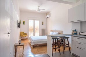 A room with a bed, a small table, a bar area with stools, a ceiling fan, and a window with a view. - Zen Intimate, Exarchia (Athens City)
