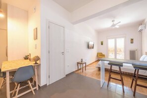 A modern kitchen with a wooden table and chairs, a small stool, and a window with a view. - Zen Intimate, Exarchia (Athens City)