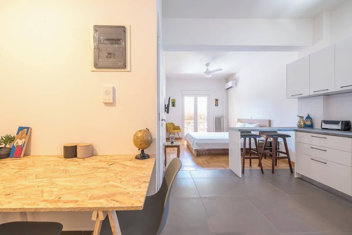Una cocina moderna con armarios blancos, una zona de comedor con una mesa de madera y un globo terráqueo a la vista en la pared.
