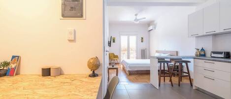 Una cocina moderna con armarios blancos, una zona de comedor con una mesa de madera y un globo terráqueo a la vista en la pared.