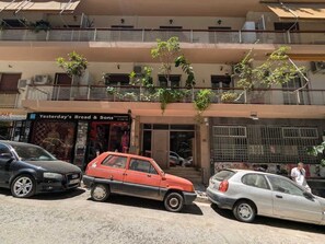 A street view with parked cars, a building with a storefront, and a balcony with plants. - Zen Intimate, Exarchia (Athens City)