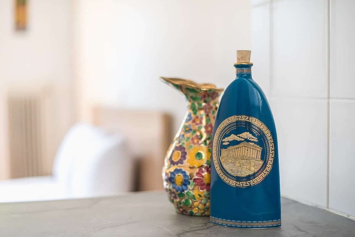 A blue bottle with a decorative label and a colorful vase on a table.
