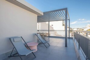 A balcony with two lounge chairs and a small table, a pergola structure, and a view of the cityscape. - Zen Epsilon, Zografou (Athens)