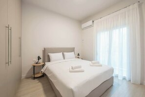 Ein Hotelzimmer mit einem großen Bett, einem Nachttisch mit Lampe und einem Fenster mit Vorhängen.