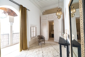 Ein Zimmer mit einem zebra-gemusterten Sessel, einem schwarzen Tisch mit Spiegel und einem weißen Teppich.