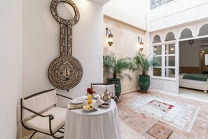 Un'area pranzo con un tavolo apparecchiato per la colazione, un elemento decorativo a parete e piante in vaso.
