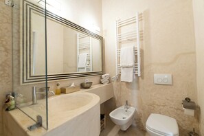 Un bagno con un lavandino spazioso, un bidet, un water, uno specchio e porta asciugamani.