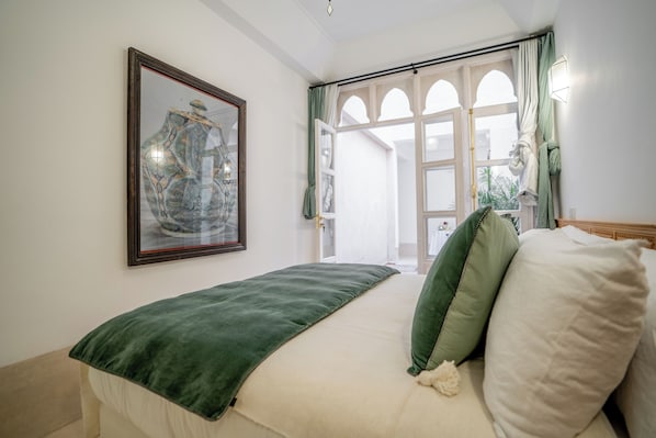 A bedroom with a bed, a framed artwork, and a view of an outdoor area.