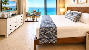 A hotel room with a bed, a TV, a balcony with a view of the ocean, and a desk with a chair. - Mahana Villas | Oceanfront 2 Bedroom Sleeps 5 | Car Incl. w/ 6+ Nights | MAH ML-4196 by KBM (Lahaina)