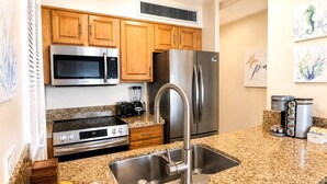 A kitchen with wooden cabinets, stainless steel appliances, a granite countertop, and a bowl of lemons. - Mahana Villas | Oceanfront 2 Bedroom Sleeps 5 | Car Incl. w/ 6+ Nights | MAH ML-4196 by KBM (Lahaina)