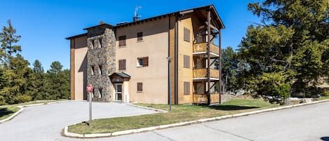 Ein mehrstöckiges Gebäude mit einer steinernen Fassade, hölzernen Balkonen und blauem Himmel.