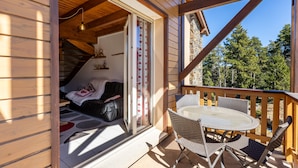 Een houten chalet met een balkon, een eettafel en een bank.